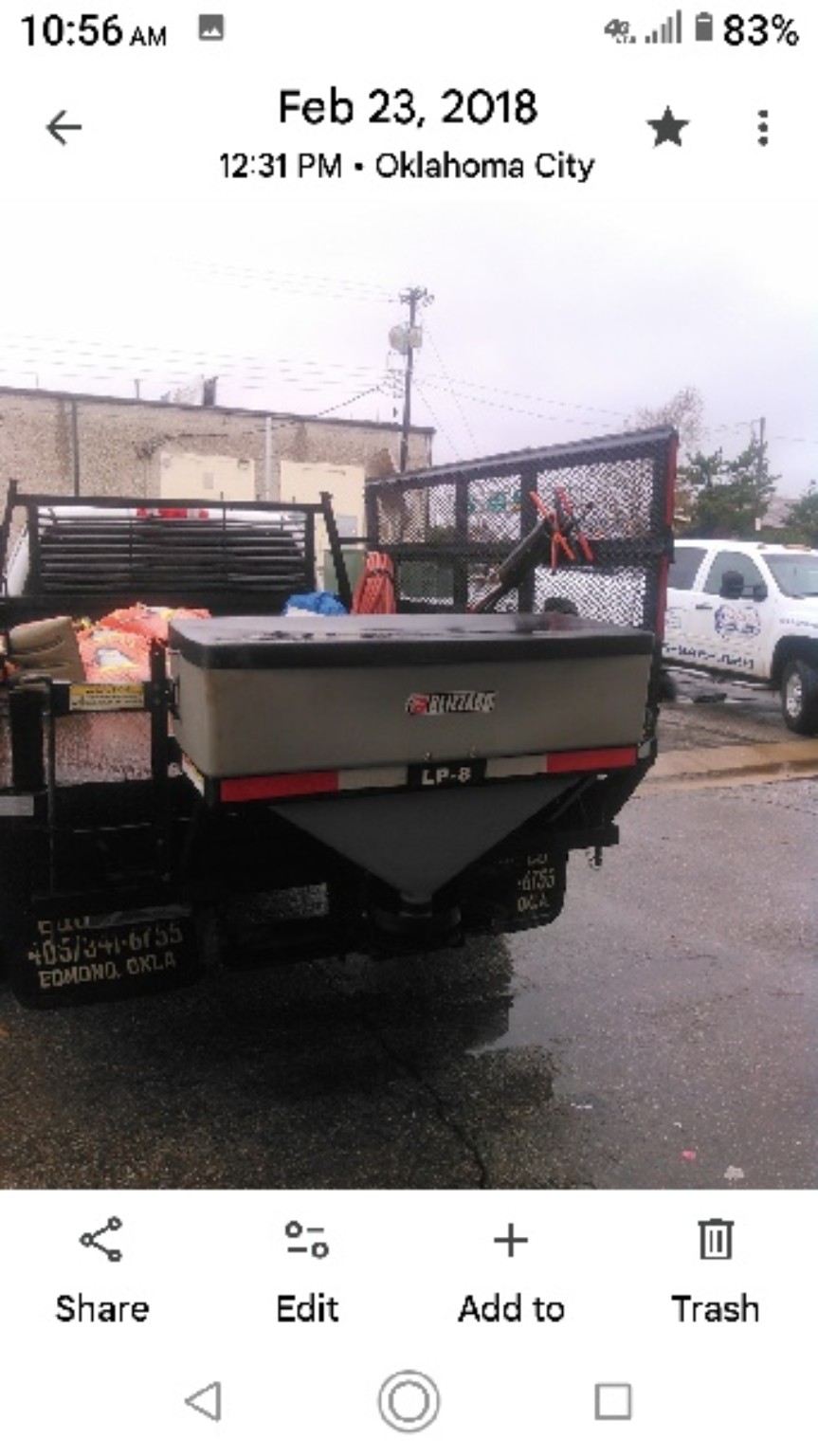 A hopper spreader mounted on the rear of a utility truck.